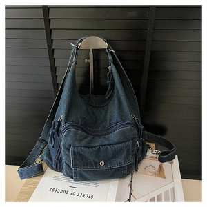 Detail of dark blue denim crossbody bag with multiple pockets and metal hardware