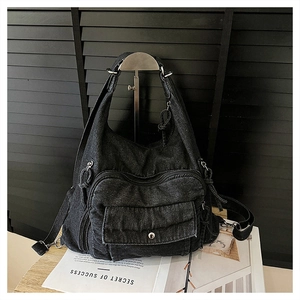Detail of black denim tote backpack with multi-pocket design and vintage metal hardware