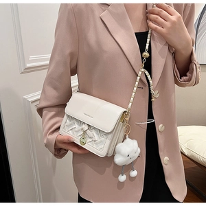 Detail view of cream white woven crossbody bag with cute cloud charm and gold chain strap