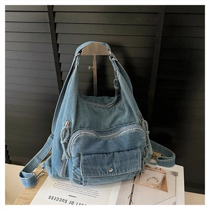 Detail of blue denim backpack showing heart-shaped zipper pocket and metal snap button