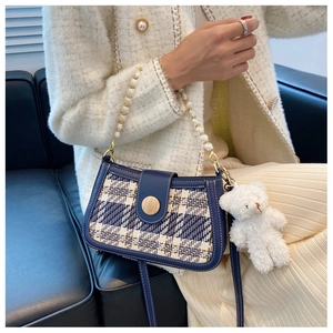 Detail of tweed crossbody bag with pearl chain and cute white bear pendant charm