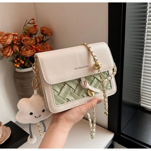Detail of woven faux leather square bag with gold chain and cloud pendant decor