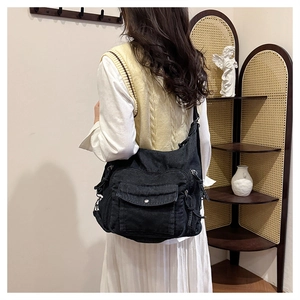 Close-up of black denim multi-pocket crossbody bag in a cozy indoor lifestyle setting