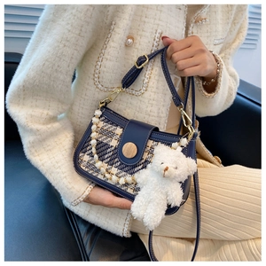 Close-up of navy plaid crossbody bag featuring a pearl chain and plush bear charm