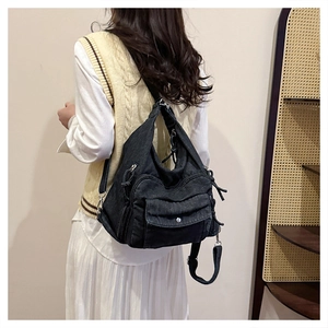 Detail view of washed denim backpack on model in a minimalist natural setting