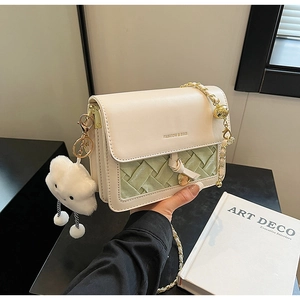 Detail of cream and green woven crossbody bag with gold chain and plush cloud charm