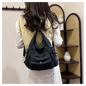 Rear view of model wearing a vintage black denim backpack with multi-pocket design
