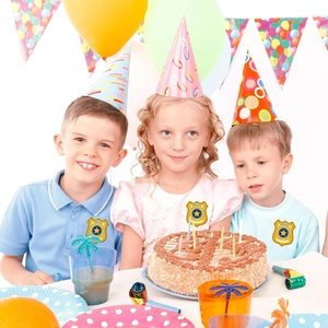 Gros plan d'enfants portant des autocollants d'insignes de police lors d'une fête d'anniversaire