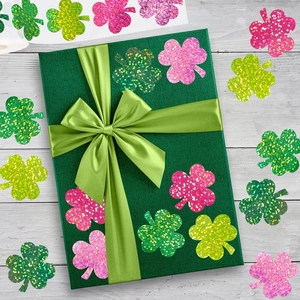 Close-up of colorful glitter clover stickers on a gift box with wooden background