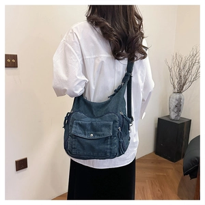 Detailed side view of a large navy denim hobo bag with adjustable strap and pockets