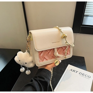Close-up of cream and pink woven crossbody bag with metal chain and plush cloud charm