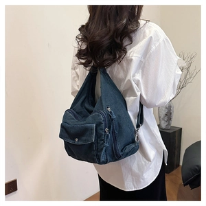 Detail of blue denim backpack showing side zipper pockets and functional metal hardware
