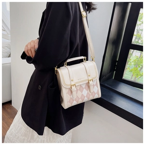 Detail of a vintage cream leather crossbody bag with pink argyle flap and gold accents