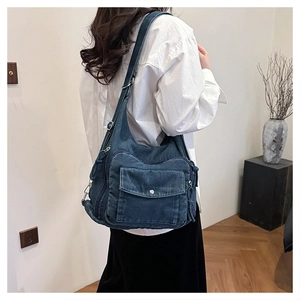 Detail of a large dark blue denim tote bag with silver snap pocket and washed texture