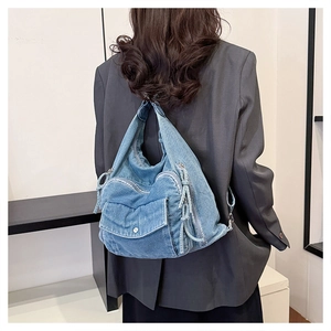 Blue denim crossbody tote bag with multiple pockets worn by model in casual setting