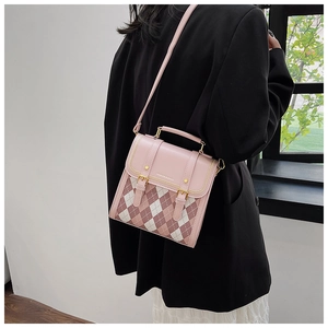 Detail view of mini pink argyle shoulder bag with gold hardware and top handle strap