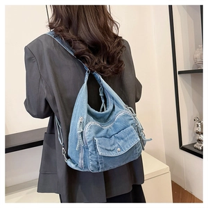 Back view of light blue denim backpack showing multi-pocket design and wash texture