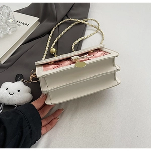 Detail of crossbody bag with pink satin weave, gold buckle, and plush cloud charm
