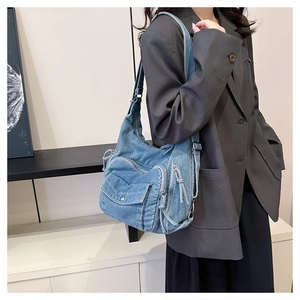 Detail of light blue washed denim shoulder bag with utility pockets and wide strap