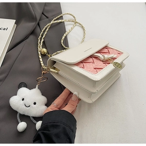 Detail of color-block woven crossbody bag with gold chain and plush cloud charm