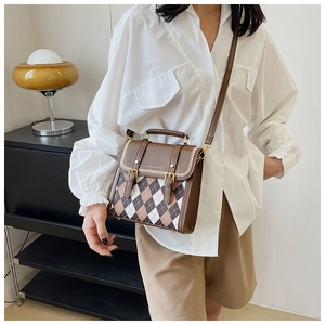 Detail of a brown quilted leather crossbody bag featuring classic plaid pattern and gold hardware