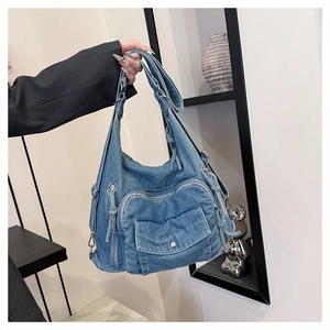 Detail view of blue washed denim tote bag with multi-pocket design and silver hardware