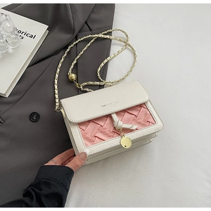 Detail of crossbody bag featuring pink woven texture and adjustable gold chain strap