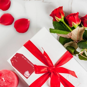 Rood cadeaulabel met Be My Valentine tekst op witte doos met rozen en kaarsen