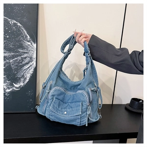 Detail of light blue denim tote bag with multiple zipper pockets and metal buckles