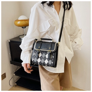Detail of vintage messenger bag featuring diamond pattern and gold metal buckle straps