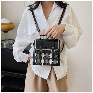 Detail of quilted color-block backpack with golden chain trim and metal buckle closure