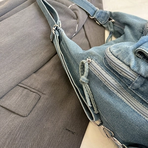 Minimalist denim shoulder bag in light blue with silver hardware and utility pockets