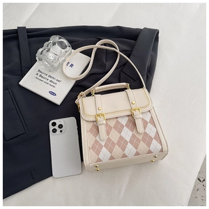 Detail of quilted beige messenger bag with pink diamond pattern and metallic buckles