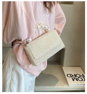 Detailed view of handmade pearl woven handbag featuring oversized pearl handle accents