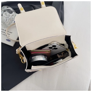 Detail showing the spacious interior of the cream leather bag with daily essentials