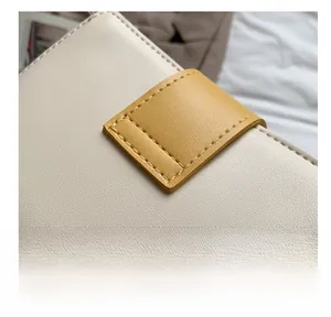 Détail des coutures précises sur le sac seau en similicuir crème et jaune