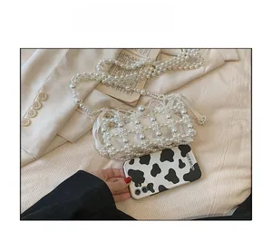 Detailed size comparison of the white pearl woven mini bag next to a smartphone
