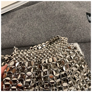 Detail of silver metallic hollow-out woven pattern with round beads on a fashion handbag
