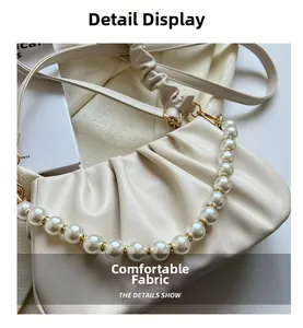 Detail view of off-white pleated bag with pearl strap and golden hardware accents