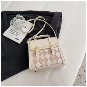 Detail of quilted diamond pattern on cream and pink crossbody bag with gold buckle hardware