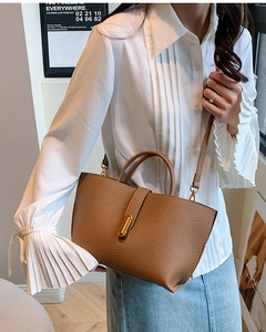 Close-up of brown pebbled leather tote bag with elegant gold metal twist lock detail