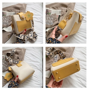 Vue détaillée du petit sac bandoulière beige et jaune avec bandoulière et breloque