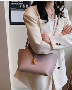 Detail of lychee pattern leather handbag with gold oval twist lock and adjustable strap
