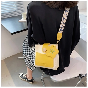 Détail du sac seau jaune et blanc avec bouton en bois et breloque fleurie sur modèle
