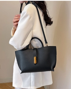 Detail of black pebbled leather tote bag with gold bar clasp and adjustable shoulder strap