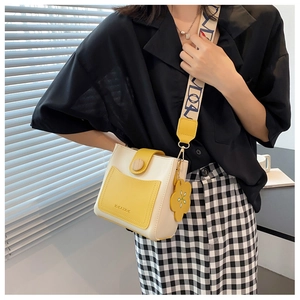 Détail d'un sac seau bandoulière jaune et blanc avec une large sangle à motifs chic