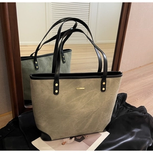 Detail of olive green suede tote bag with black leather trim and gold rivet accents