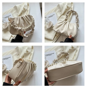 Detail of beige pleated cloud bag showing pearl chain handle and leather strap textures