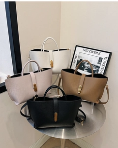 Close-up of four large faux leather tote bags in white, pink, brown, and black colors