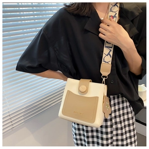 Détail du sac seau bicolore crème avec bandoulière jacquard et breloque fleurie